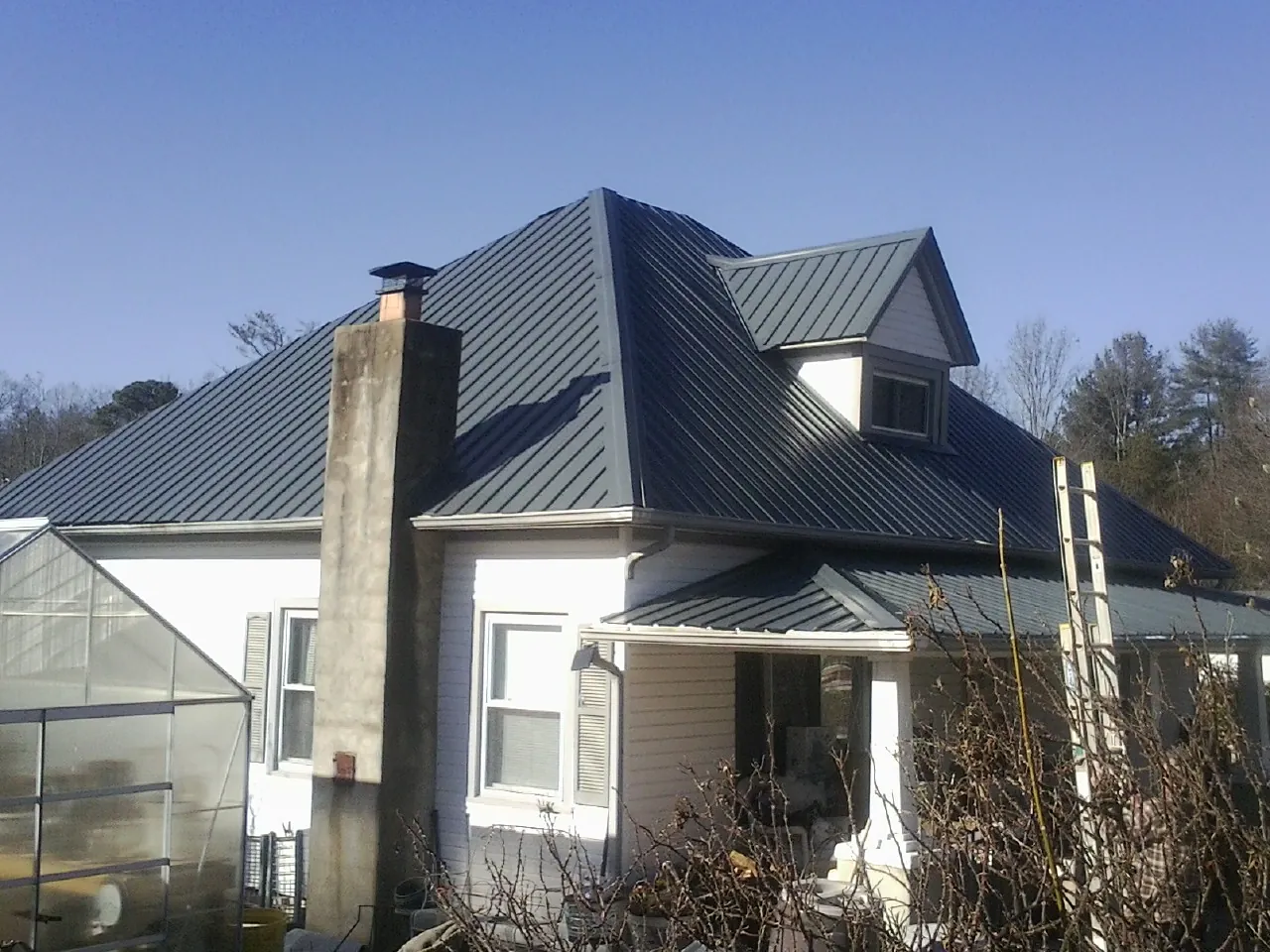Dark blue standing seam metal roof on a white farmhouse with dormer — Slate & Tile Roof Repair by Roofing Brothers in Stoutsville