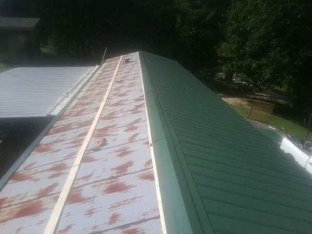 Old rusted panels beside newly installed green metal roofing — Wind Damage Roof Repair by Roofing Brothers in Stoutsville