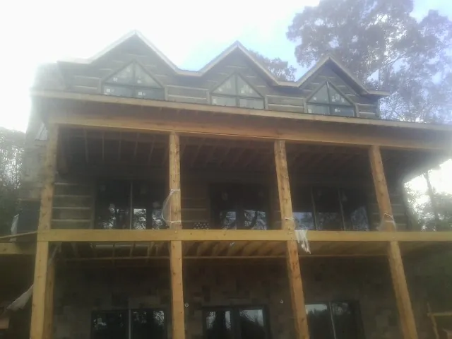 Dormers and porch framing on a large log home under construction — Roof Coating work by our crew in Stoutsville