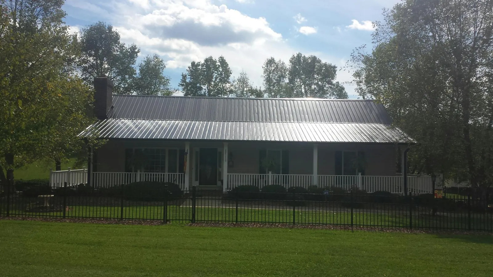 Gray metal roof on a brick ranch with a full width front porch — Gutter Guard Installation work by our crew in Stoutsville