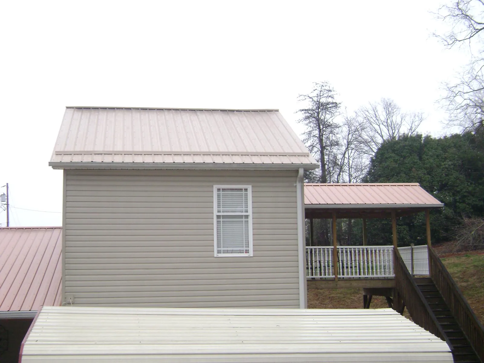 Tan metal roofs on a two story addition and attached porch, from a Roof Replacement job in Stoutsville