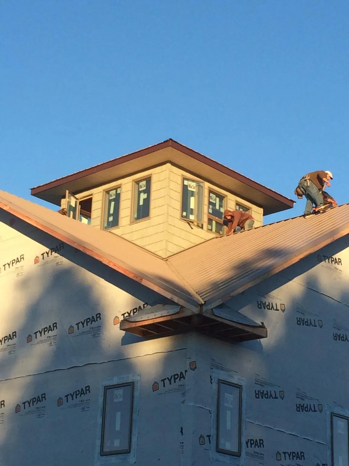 Roofers working around a rooftop cupola on a new metal roof at sunset — Roof Waterproofing in Stoutsville by Roofing Brothers